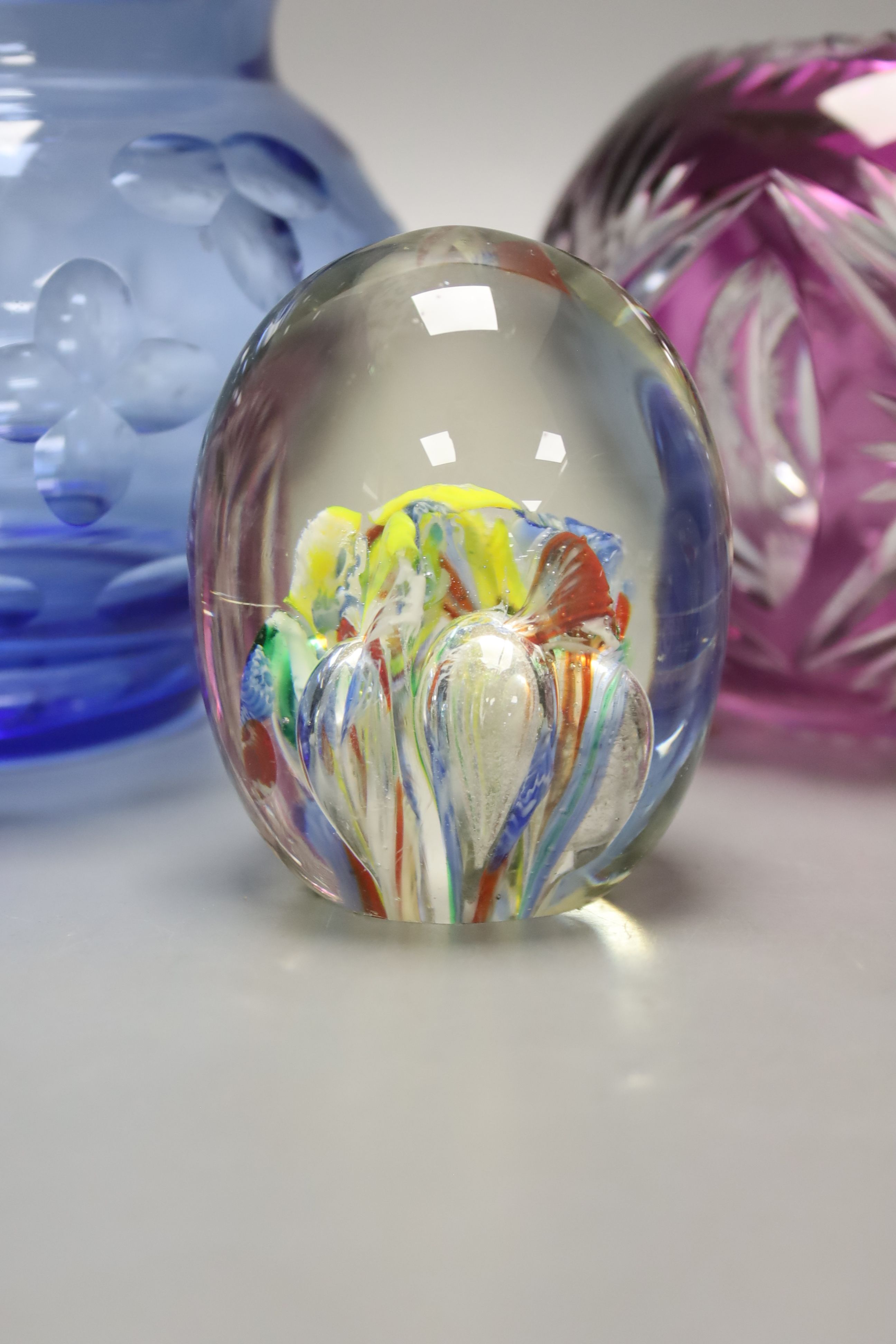 A group of coloured glassware including paperweights